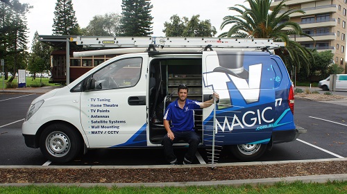 technician sitting in side door of his van with an antenna in his hand
