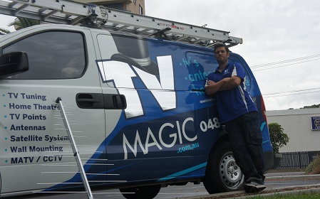 technician next to his TV Magic van with an antenna leaning up against the front of van