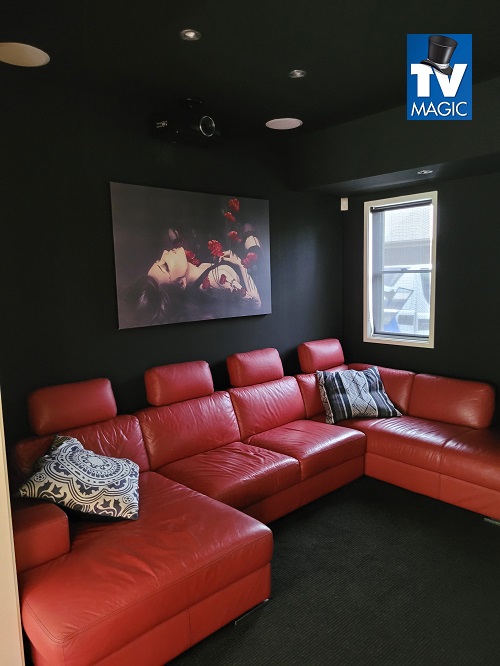 a fully themed home theate in red and black with a TV Magic logo in top right corner