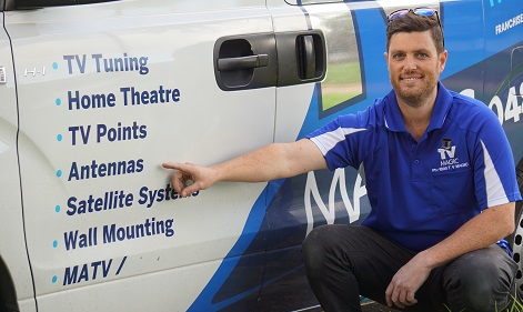 technician pointing to the services menu on the side of his TV Magic van - specifically pointing at antennas service