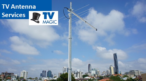 an antenna with tall buildings in the background and a TV Magic logo in top right corner, over lapping the words TV antenna services