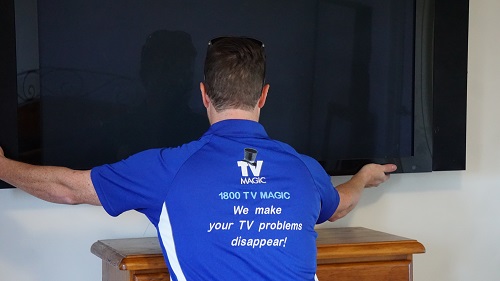 a technician installing a TV - mounted on a wall.