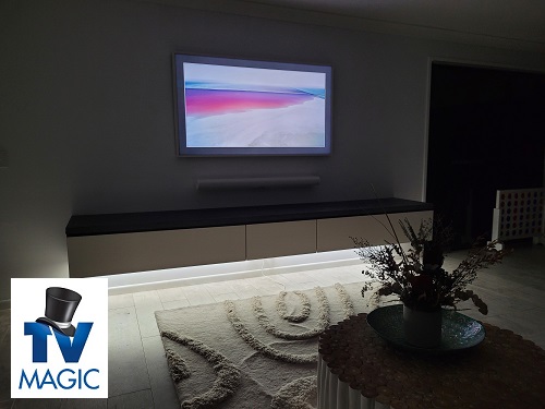 a stunning Samsung Frame TV mounted on a wall with a floating sound bar. TV Magic logo in bottom left corner
