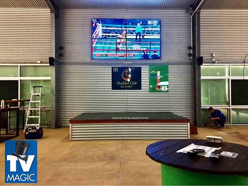 a partially completed multi-TV display in a commercial setting, with a TV Magic logo in bottom left corner