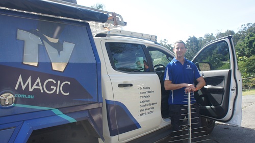 Technician standing next to his van holding an aerial