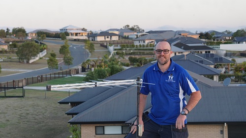 Technician on a roof with one of his antenna relocation services