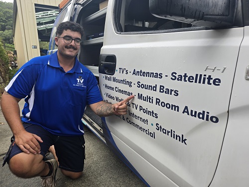 Technician Kyle, pointing to his services on the side of his van.
