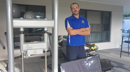 technician with a TV ready to install in a gym