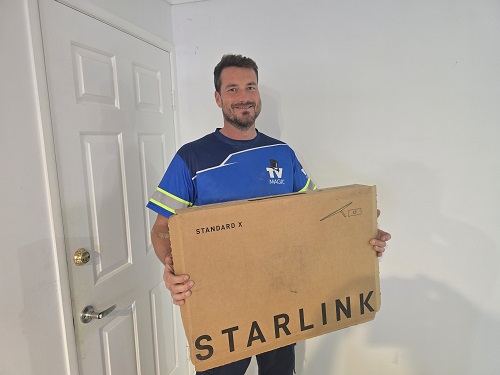 Technician holding a Starlink kit ready for installation.