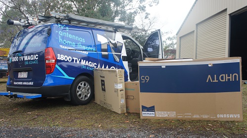 a picture of techncian's van with various boxed TVs