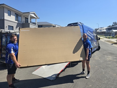 Technicians moving a massive TV, ready for delivery