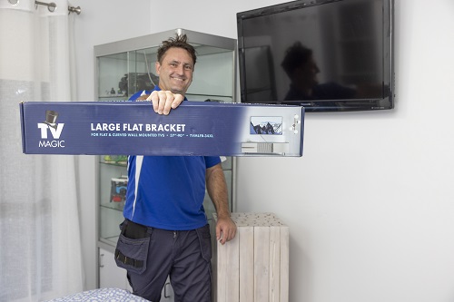 Technician holding up a wall bracket in front of a wall mounted TV