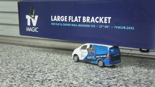 Close up of a TV Magic wall bracket with a TV Magic mini van in front of it.