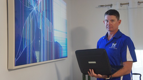 Technician next to a broken TV, performing an insurance assessment.