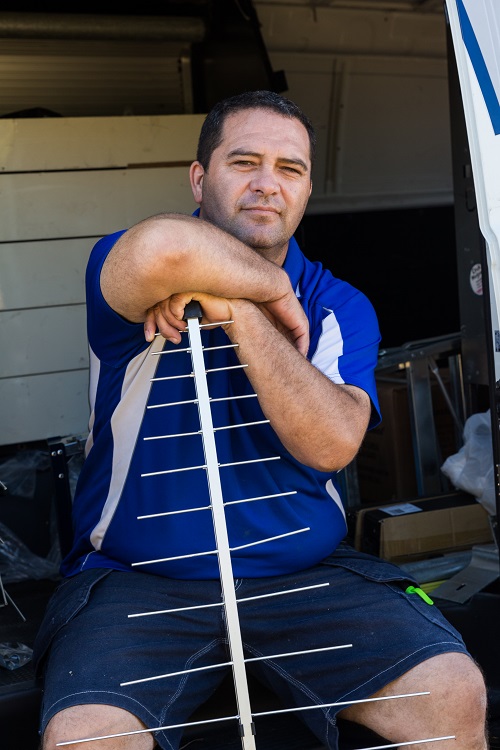 Technician - Darrel, holding an antenna seated in his van.