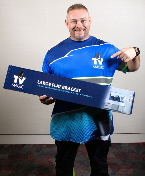 Technician holding a TV Magic wall mounting bracket, also wearing his new hi-vis uniform.