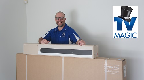 a technician with a brand new TV and sound bar ready for installation. TV Magic logo in top right corner