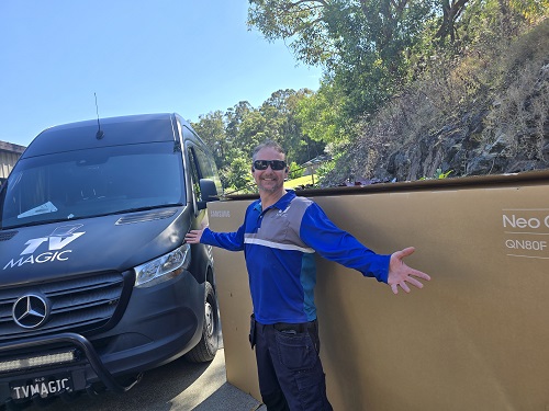 Technician showcasing a massive TV ready for delivery.