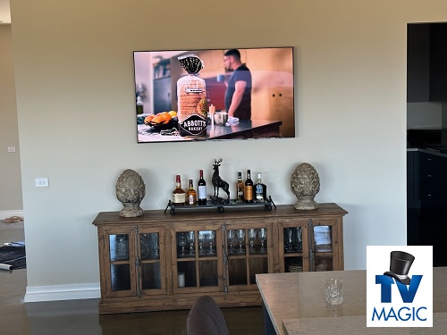 a wall mounted TV above a cabinet with a TV Magic logo in top right corner