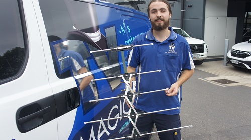 Technician with an antenna in front of his TV Magic van