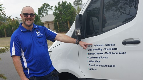 Technician pointing to his services on the side of his TV Magic van