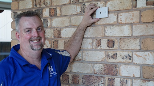 Technician holding a TV point up to a brick wall