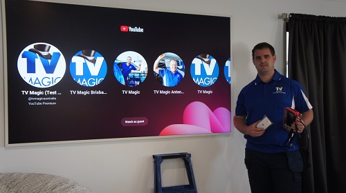 Technician next to a large TV, holding up a TV point