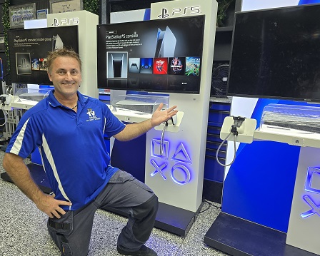 Technician in front of numerous gaming console setups for a commercial business