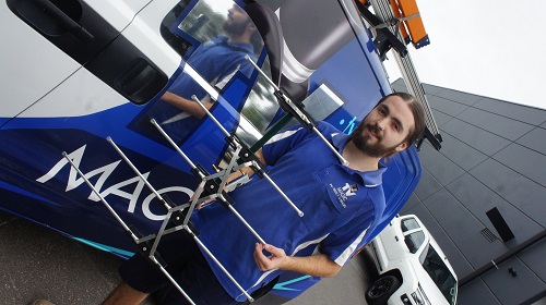 Technician holding and antenna in front of his TV Magic van