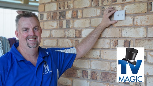 a photo of technician - Anton, holding up a TV point to a brick wall