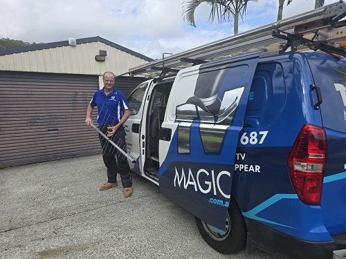 Technician holding an antenna - standing next to his vehicle.