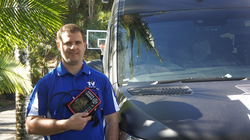 Technician with a signal meter in hand in, next to his TV Magic van