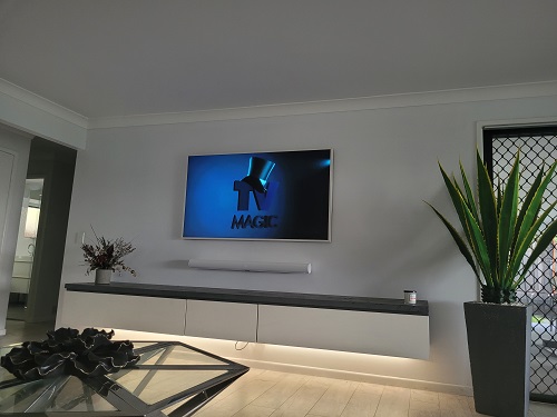 a wall mounted Samsung Frame TV and sound bar, over floating cabinet. TV Magic logo on screen