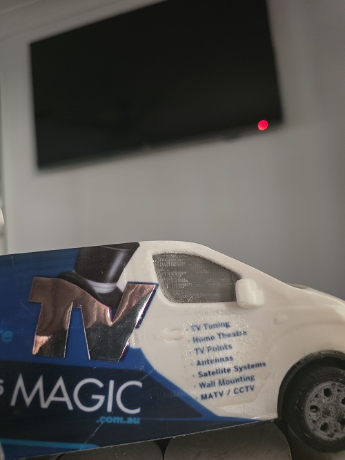 A wall mounted TV with a mini TV Magic van below