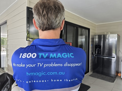 Technician showing the back of his TV Magic shirt