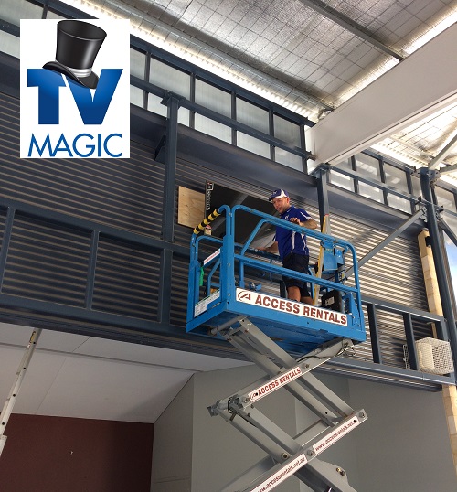 Technician performing a commercial AV service. TV Magic logo in top left corner