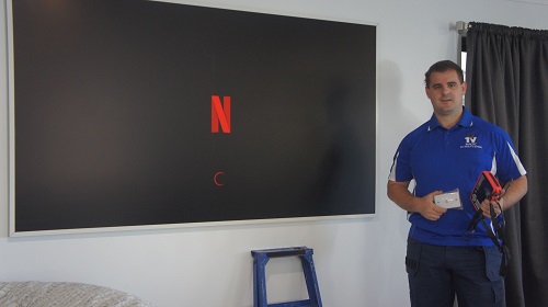 Techncian in front of a freshly wall mounted TV. Holding a TV point in hand!
