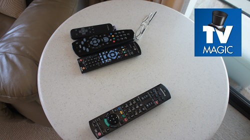 Multiple remotes on a coffee table. TV Magic logo in top right corner
