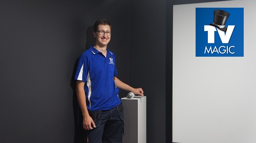 Technician next to a surround sound speaker in a home theatre by TV Magic