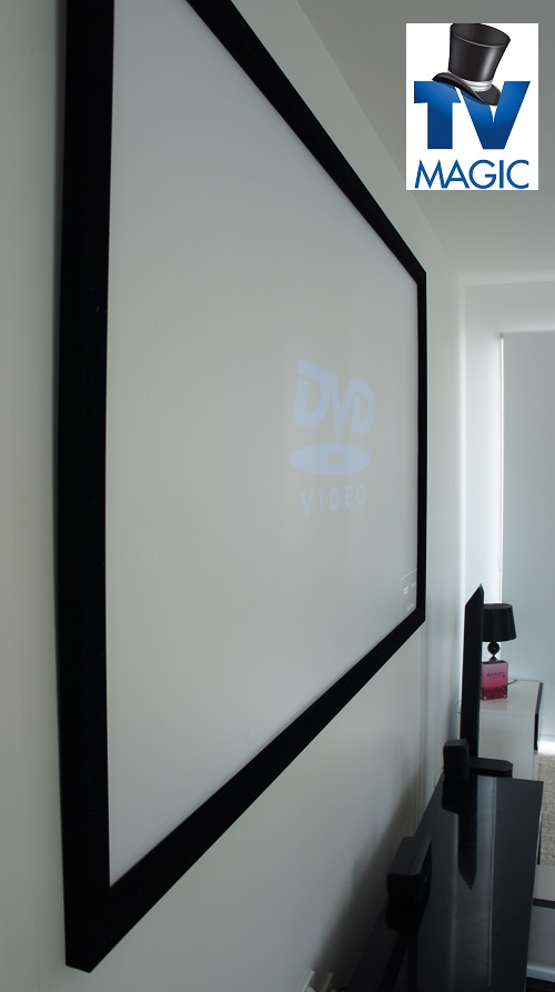 Side view of a projector screen in a TV Magic home theatre. TV Magic logo in top right corner