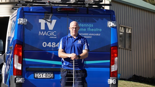 technician - Carl, standing behind his van, holding an antenna