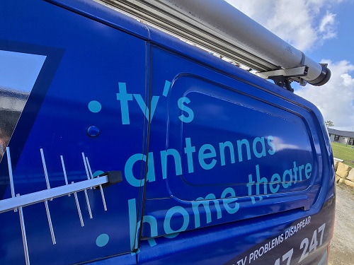 Close up of side of TV Magic van with an antenna in front of it.