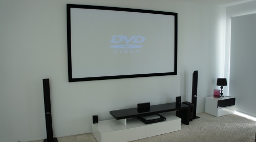 a home cinema with a projector screen and free-standing speakers