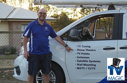 Vaughan with his van, pointing at the services menu - home theatres, with TV Magic logo in bottom right corner