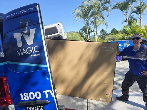 Technician loading a large TV into his TV Magic van.