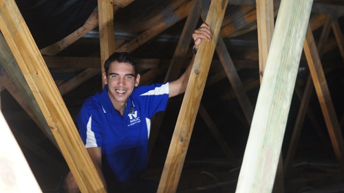 A technician in the roof of a building, attending to a pre-wire fit out