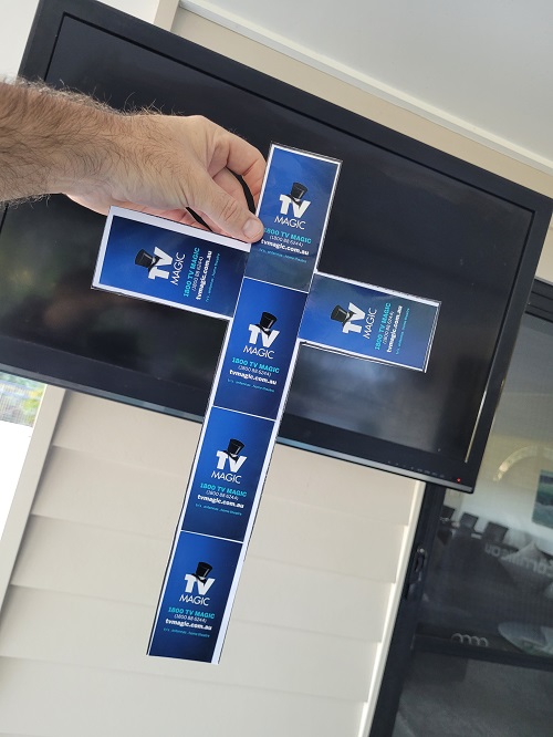 Technician holding up a cross in front of TV