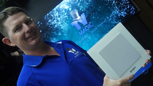 Technician holding a speaker in front of a screen