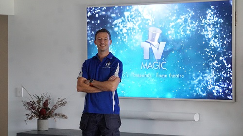 Technician in front of a large TV he tuned and setup