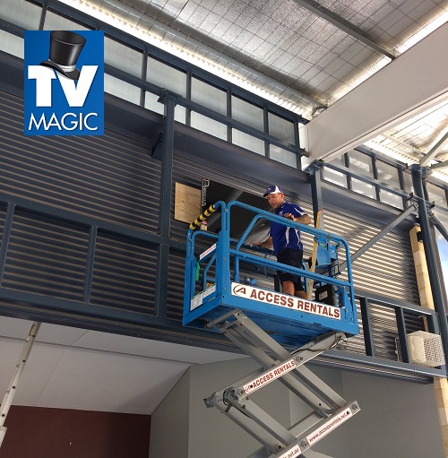 a technician on a lift installing a multi-TV display